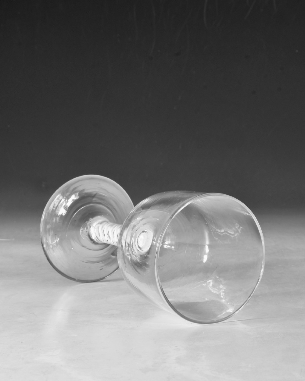 An 18th-century clear glass wine goblet featuring a round bowl supported by an opaque white spiral twist stem on a conical foot. View IV