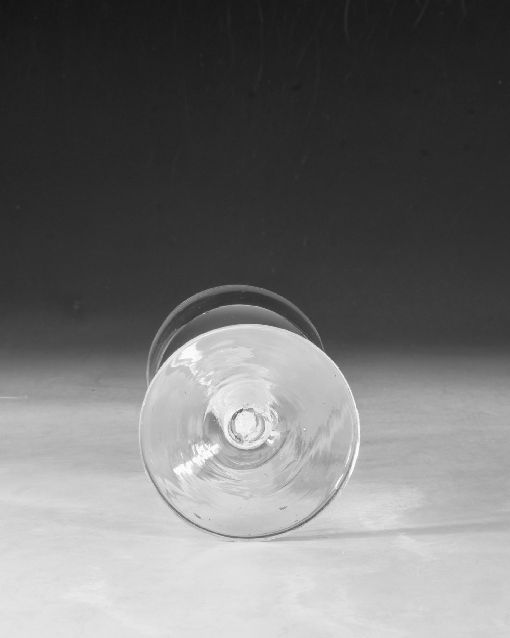 An 18th-century clear glass wine goblet featuring a round bowl supported by an opaque white spiral twist stem on a conical foot. View V