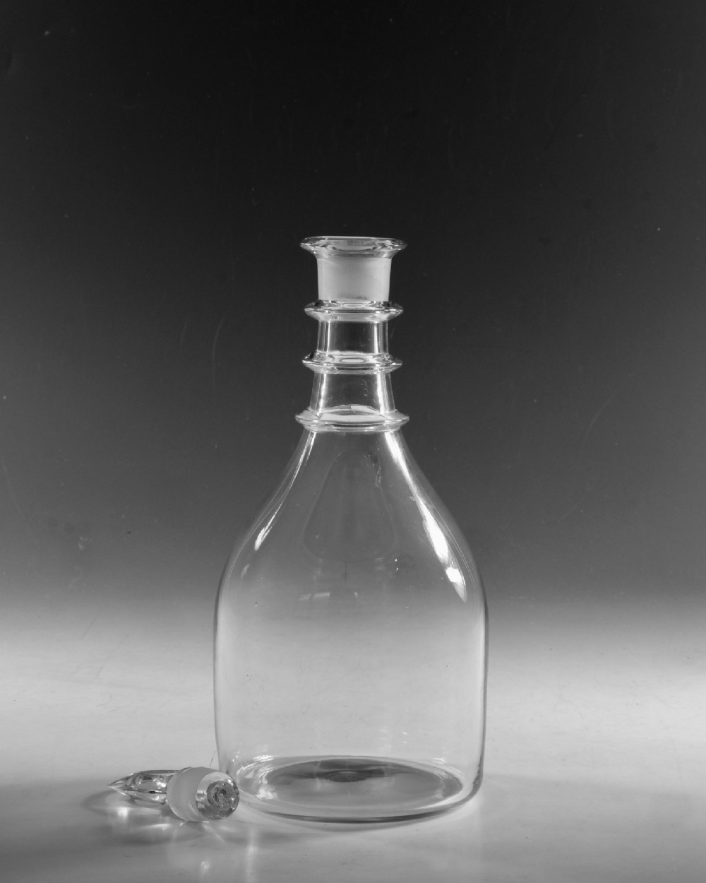 A clear Georgian glass decanter featuring three applied neck rings and a flat circular stopper. View III