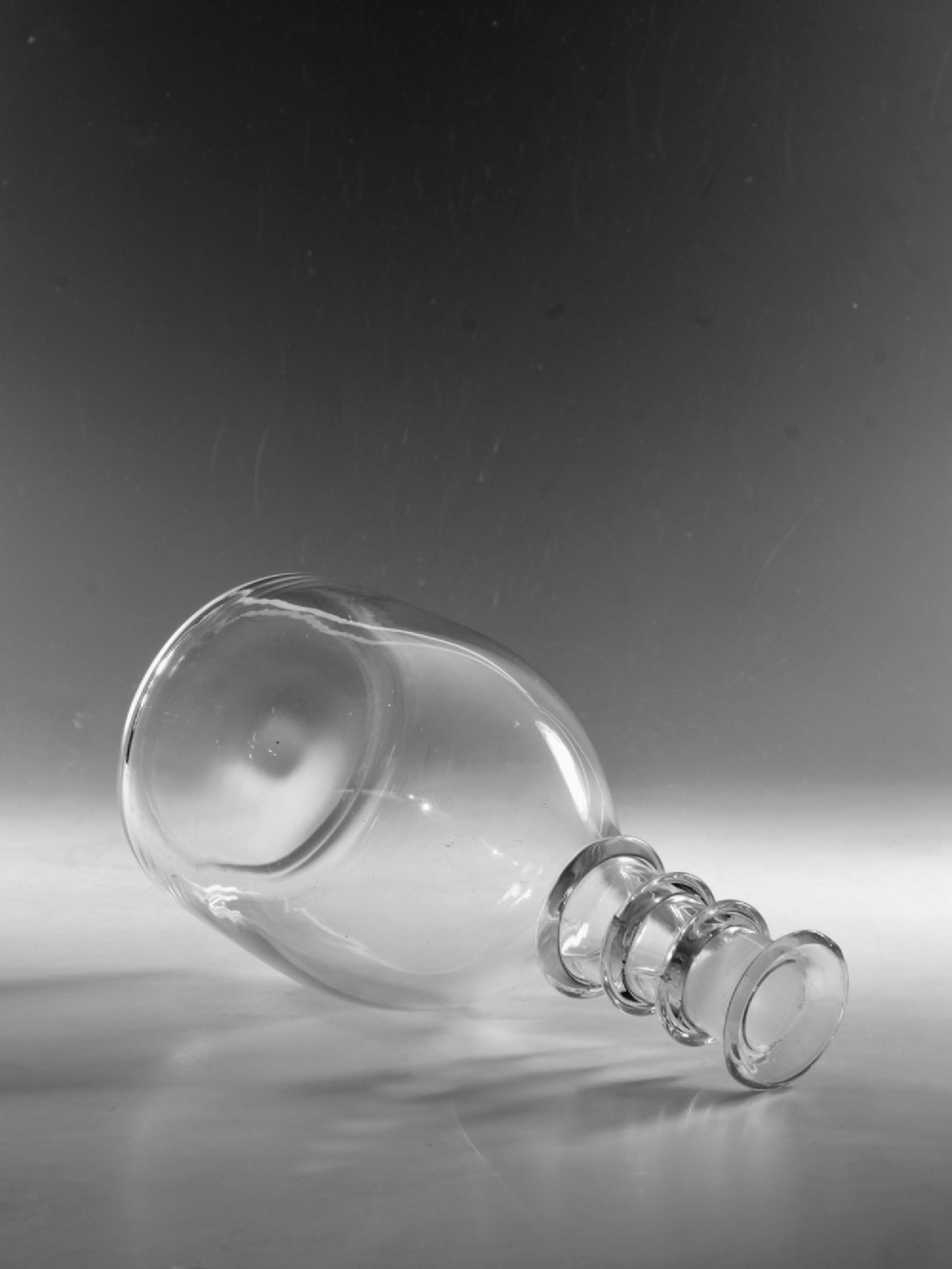 A clear Georgian glass decanter featuring three applied neck rings and a flat circular stopper. View V