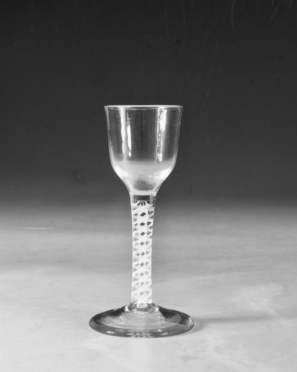 A clear Georgian lead glass wine glass featuring a tall bowl, an intricate white opaque twist stem, and a circular flat foot. View II