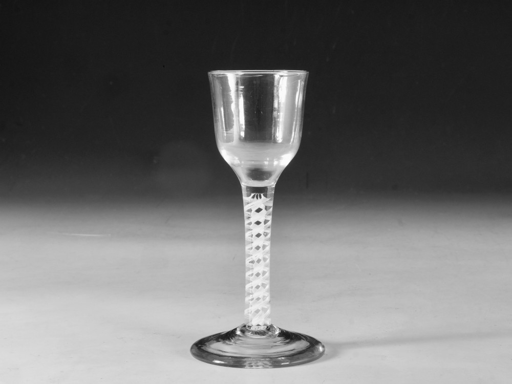 A clear Georgian lead glass wine glass featuring a tall bowl, an intricate white opaque twist stem, and a circular flat foot. View VI