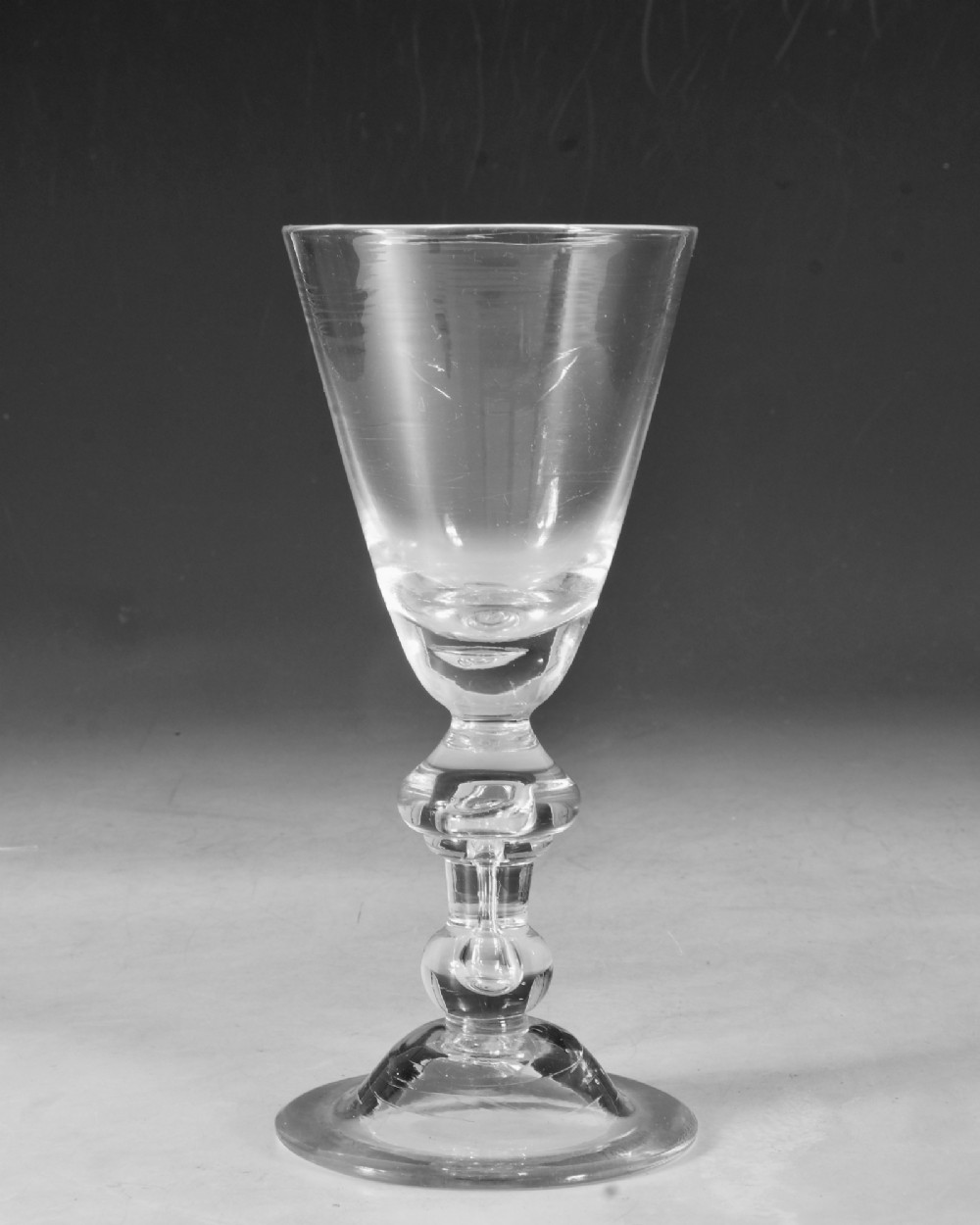 A hand-blown clear lead glass baluster wine goblet featuring a bell bowl, knopped stem with an air tear inclusion, and a folded conical foot. View III