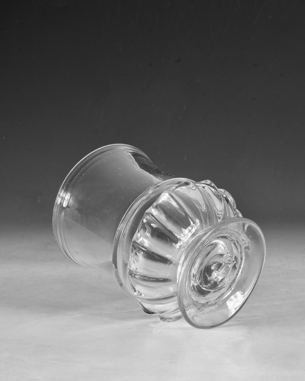 A clear 18th-century Georgian glass drinking vessel featuring a flared rim, a ribbed lower body, and a low circular pedestal base. View III