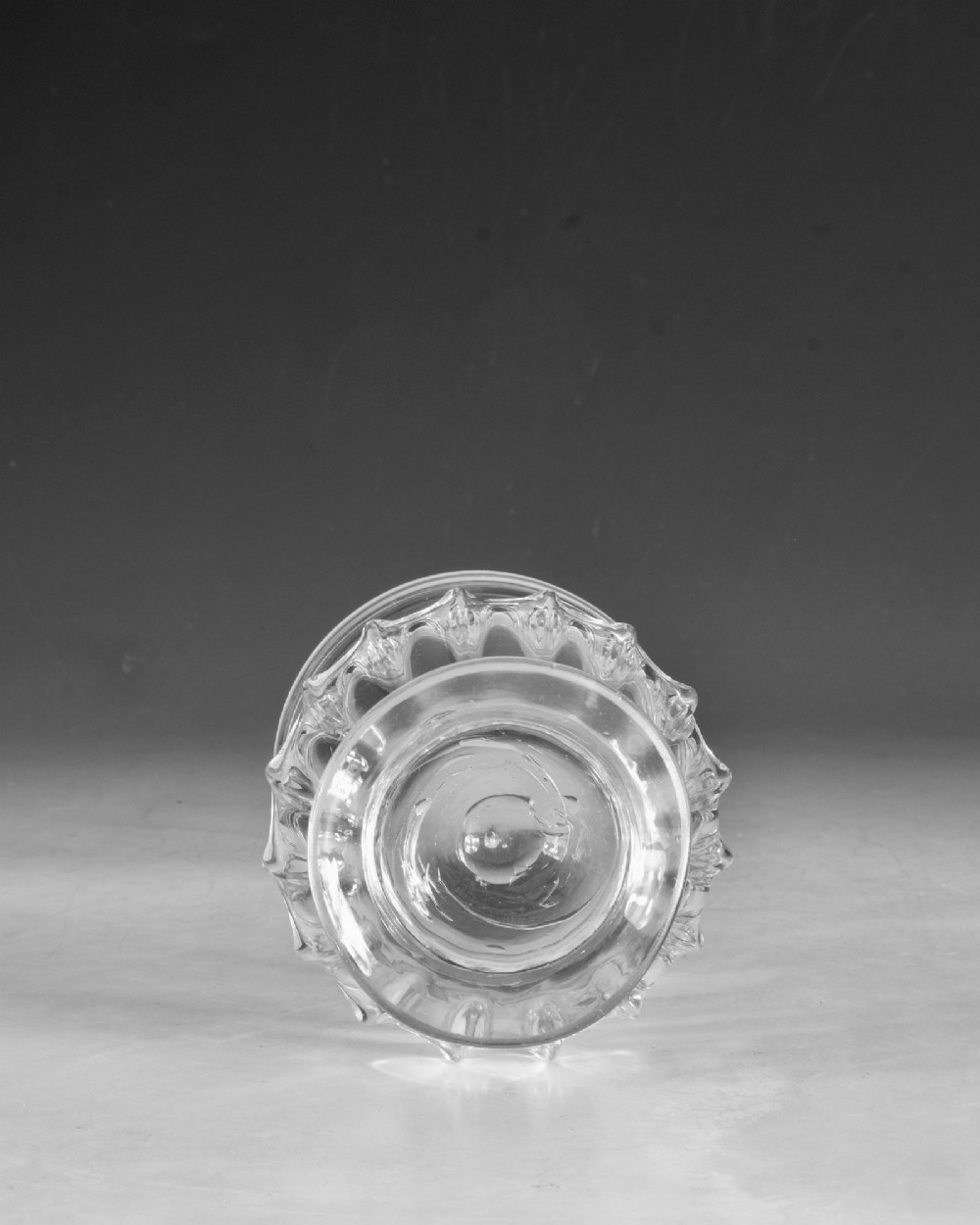 A clear 18th-century Georgian glass drinking vessel featuring a flared rim, a ribbed lower body, and a low circular pedestal base. View V