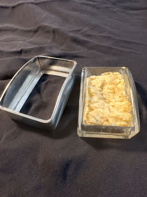 fig 1. A rectangular silver vessel with a curved rim containing a light yellow natural sponge.