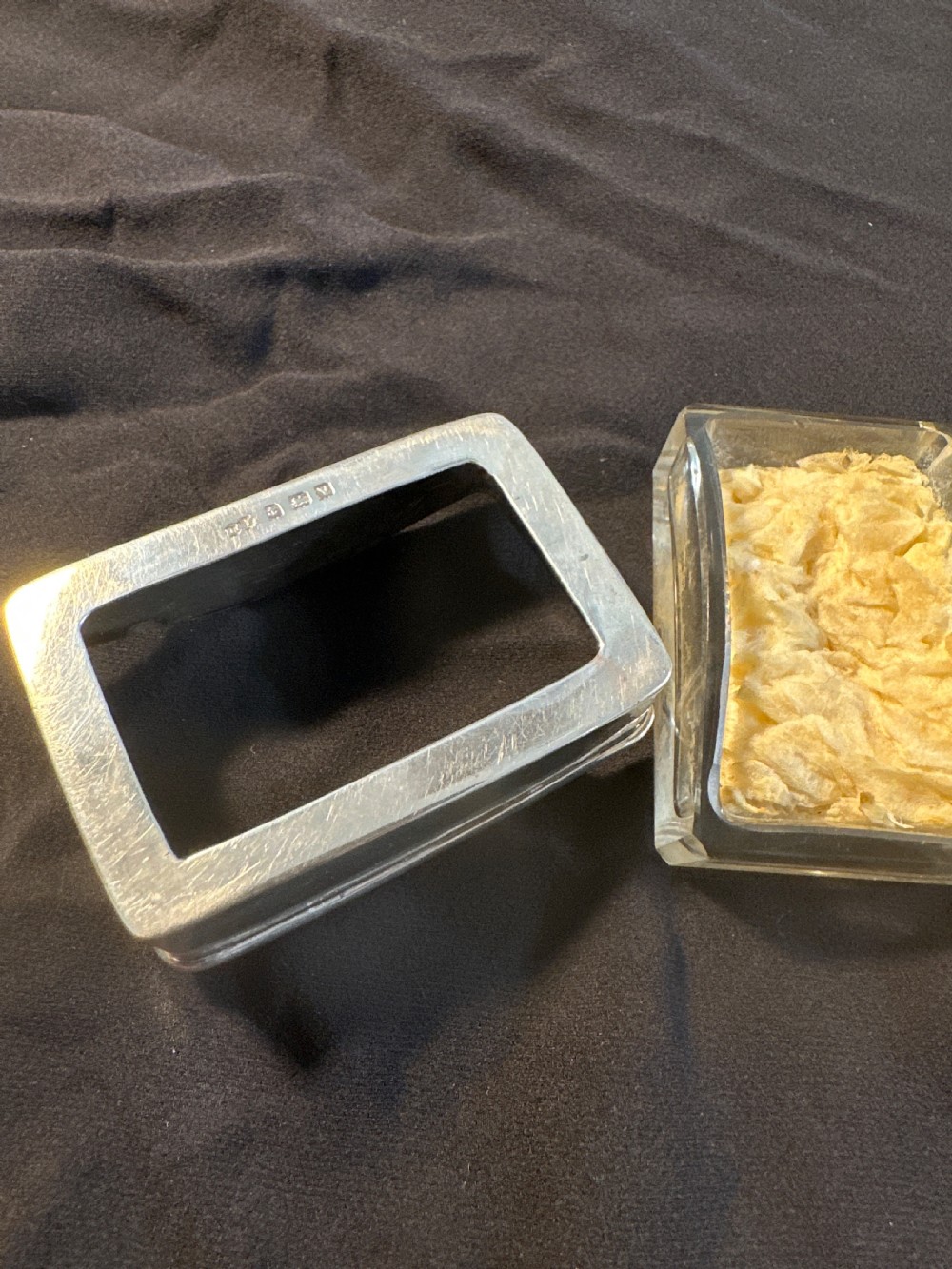 A rectangular silver vessel with a curved rim containing a light yellow natural sponge. View III
