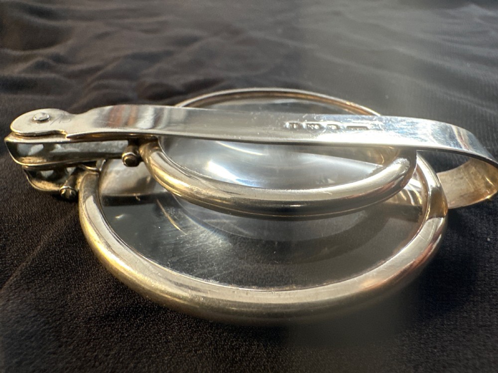 An Edwardian hallmarked sterling silver folding double-lens magnifying glass with two circular lenses attached to a hinged handle. View V