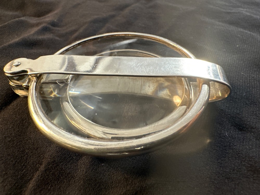 An Edwardian hallmarked sterling silver folding double-lens magnifying glass with two circular lenses attached to a hinged handle. View VI