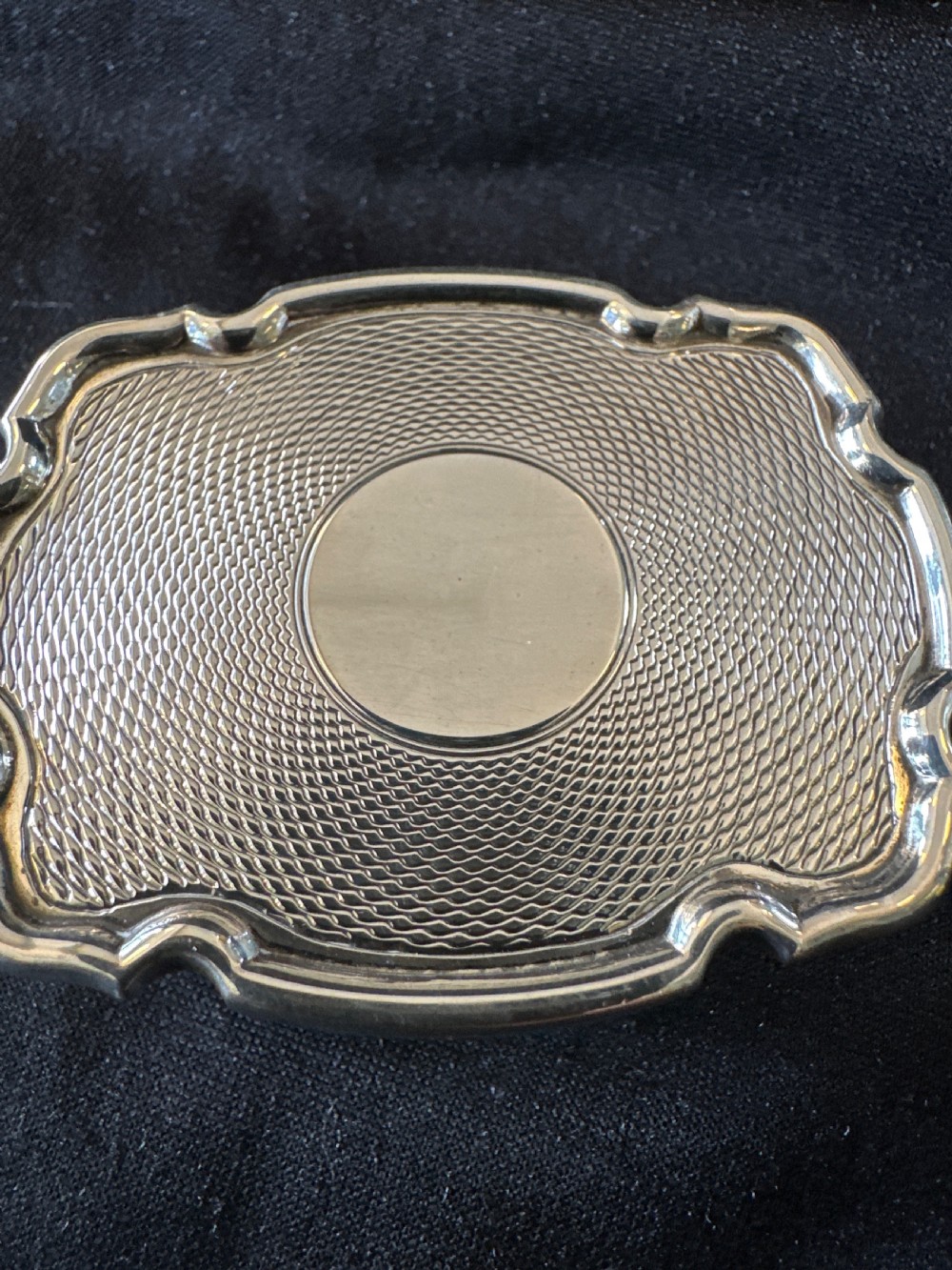 An Edwardian sterling silver shaped box with engine-turned geometric detailing on the lid and a central plain circular cartouche. View II