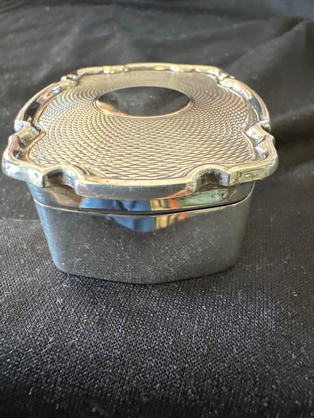 An Edwardian sterling silver shaped box with engine-turned geometric detailing on the lid and a central plain circular cartouche. View V
