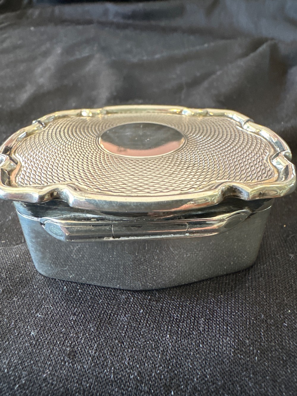 An Edwardian sterling silver shaped box with engine-turned geometric detailing on the lid and a central plain circular cartouche. View VI