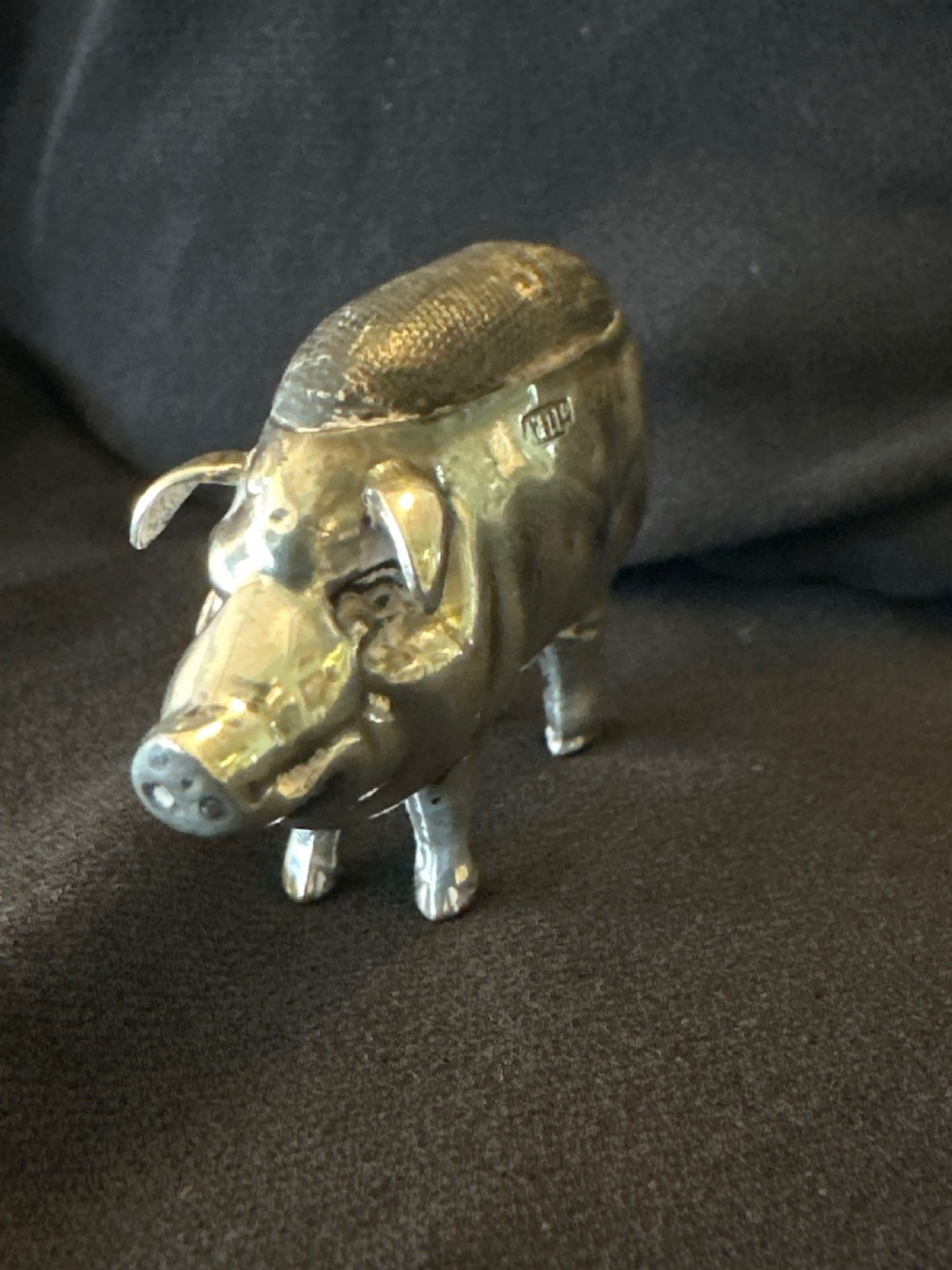 An Edwardian sterling silver pin cushion modelled in the shape of a standing pig with a fabric insert and visible hallmarked stamps on its side. View II