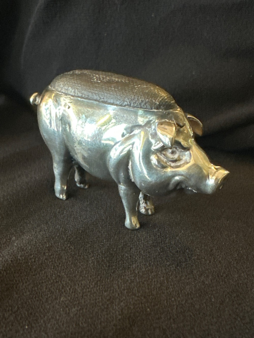 An Edwardian sterling silver pin cushion modelled in the shape of a standing pig with a fabric insert and visible hallmarked stamps on its side. View III