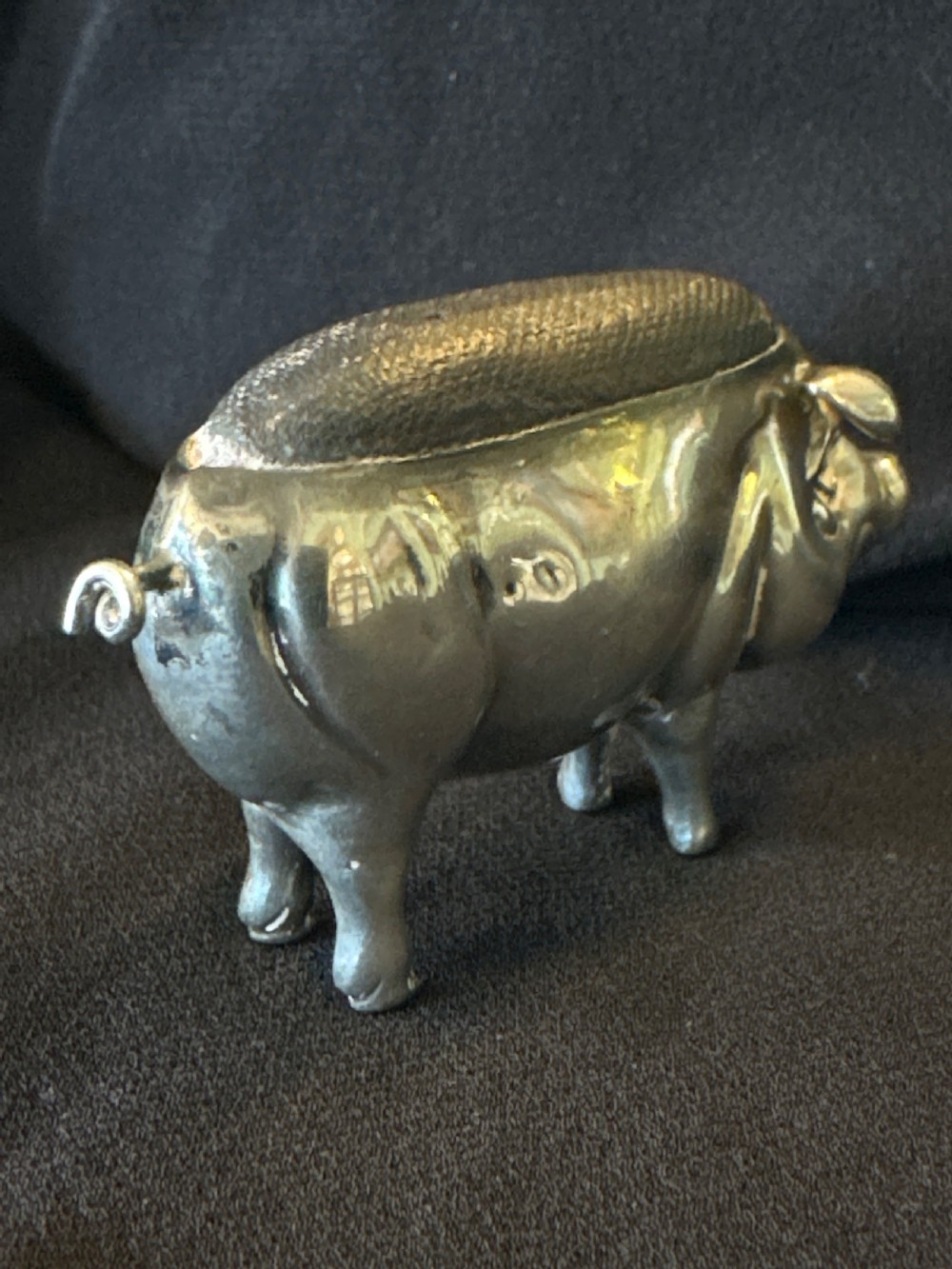 An Edwardian sterling silver pin cushion modelled in the shape of a standing pig with a fabric insert and visible hallmarked stamps on its side. View IV