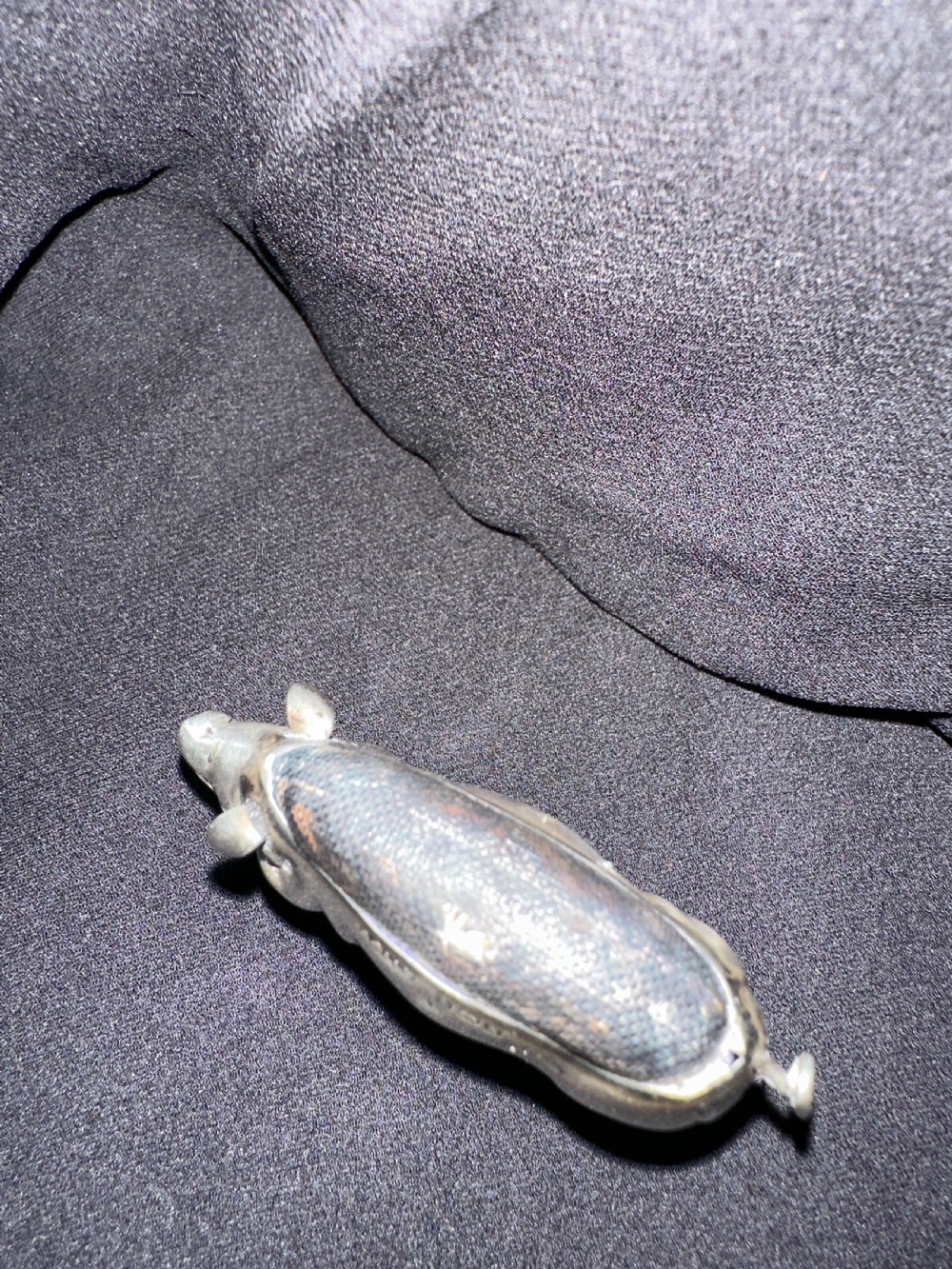 An Edwardian sterling silver pin cushion modelled in the shape of a standing pig with a fabric insert and visible hallmarked stamps on its side. View VI