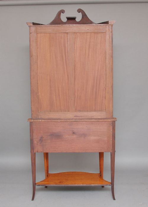 A 19th-century satinwood display cabinet featuring a swan-neck pediment, curved central glass door, and marquetry inlaid lower doors on square tapered legs. View IX