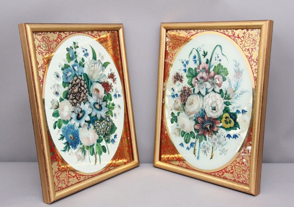 A pair of early 19th-century framed botanical paintings depicting colourful floral bouquets within oval apertures surrounded by red and gold patterned borders. View X
