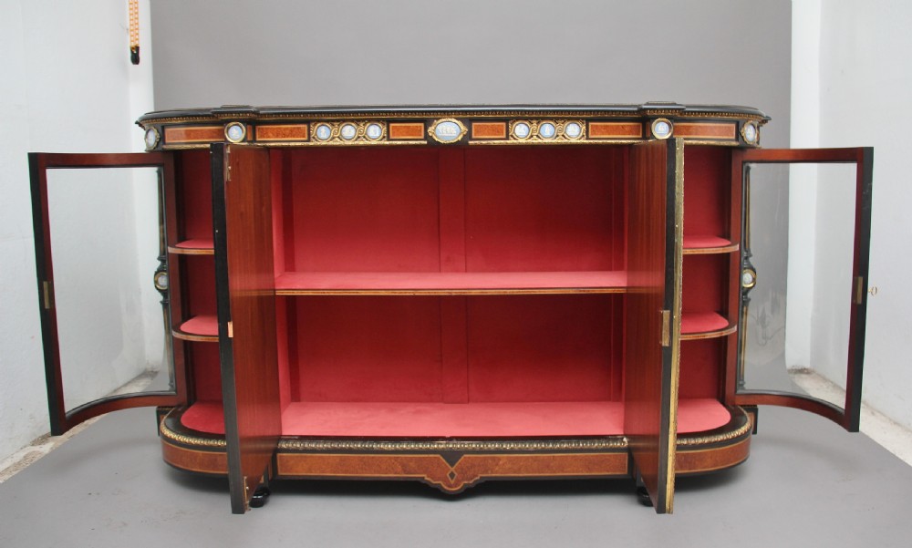 A 19th-century ebonised and amboyna wood credenza featuring central doors with oval pietre dure panels, porcelain medallion inserts, gilt bronze mounts, and curved glass side compartments. View II