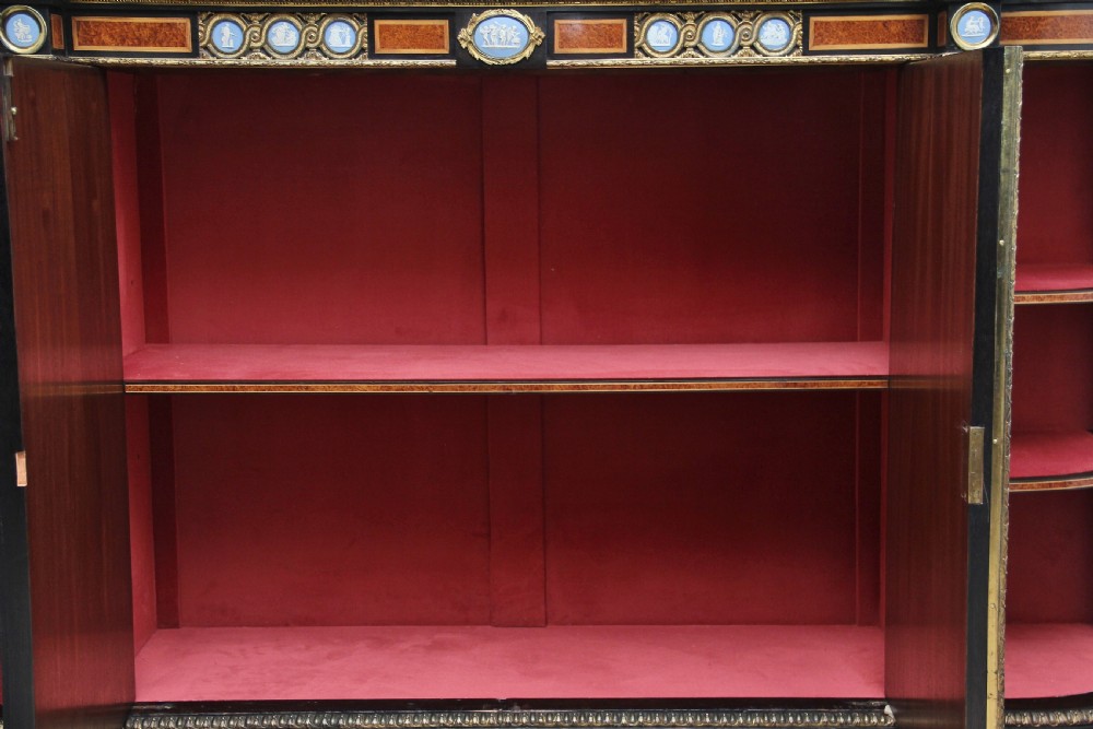 A 19th-century ebonised and amboyna wood credenza featuring central doors with oval pietre dure panels, porcelain medallion inserts, gilt bronze mounts, and curved glass side compartments. View VI