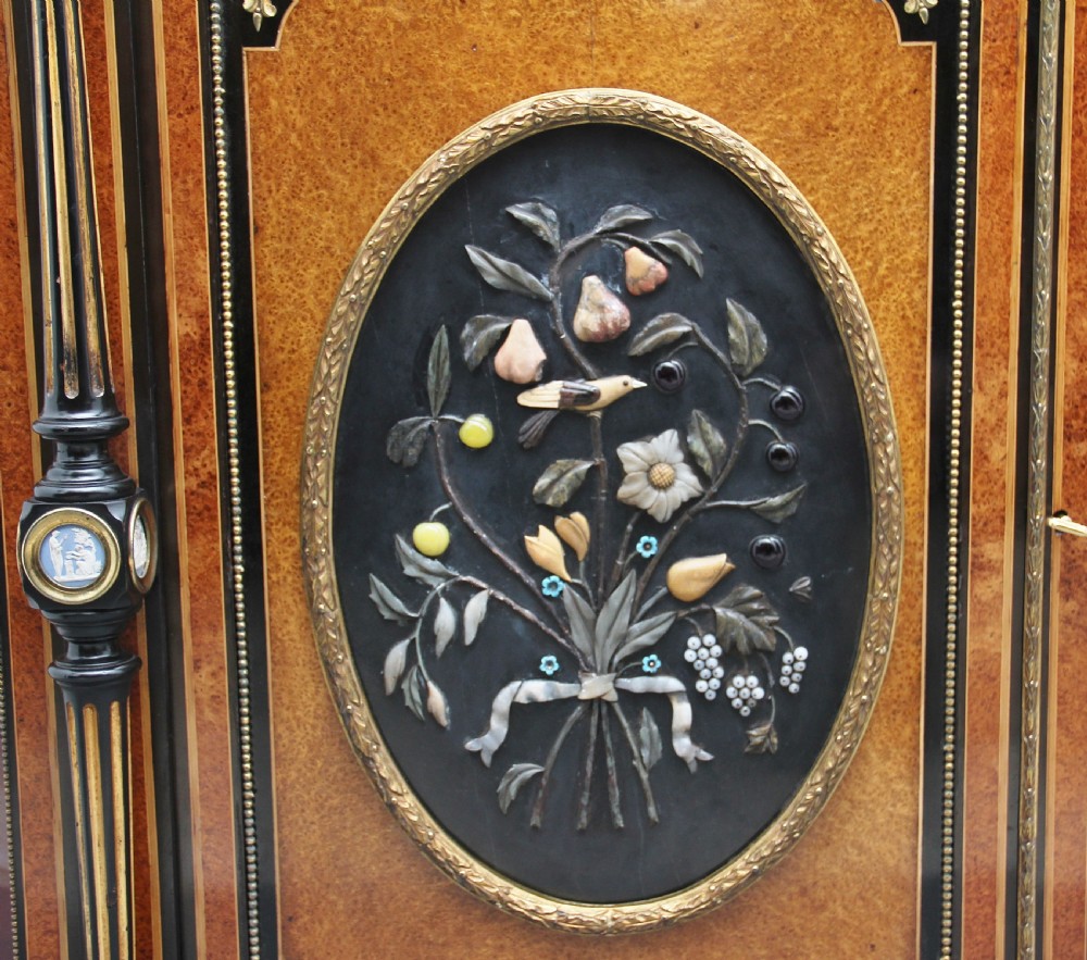 A 19th-century ebonised and amboyna wood credenza featuring central doors with oval pietre dure panels, porcelain medallion inserts, gilt bronze mounts, and curved glass side compartments. View X