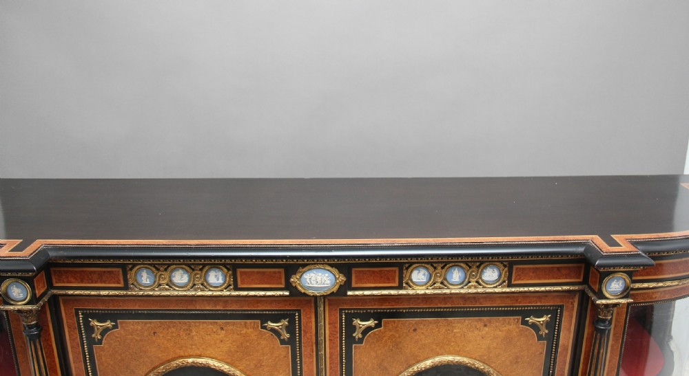 A 19th-century ebonised and amboyna wood credenza featuring central doors with oval pietre dure panels, porcelain medallion inserts, gilt bronze mounts, and curved glass side compartments. View XXI