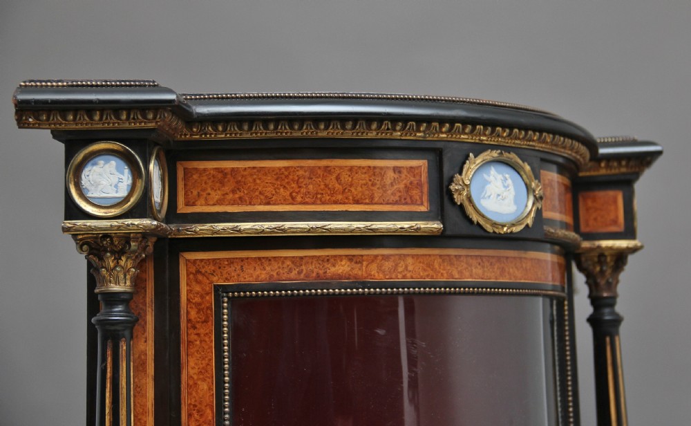 A 19th-century ebonised and amboyna wood credenza featuring central doors with oval pietre dure panels, porcelain medallion inserts, gilt bronze mounts, and curved glass side compartments. View XXII