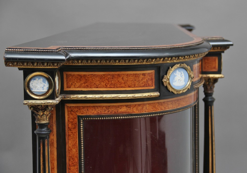 A 19th-century ebonised and amboyna wood credenza featuring central doors with oval pietre dure panels, porcelain medallion inserts, gilt bronze mounts, and curved glass side compartments. View XXIII