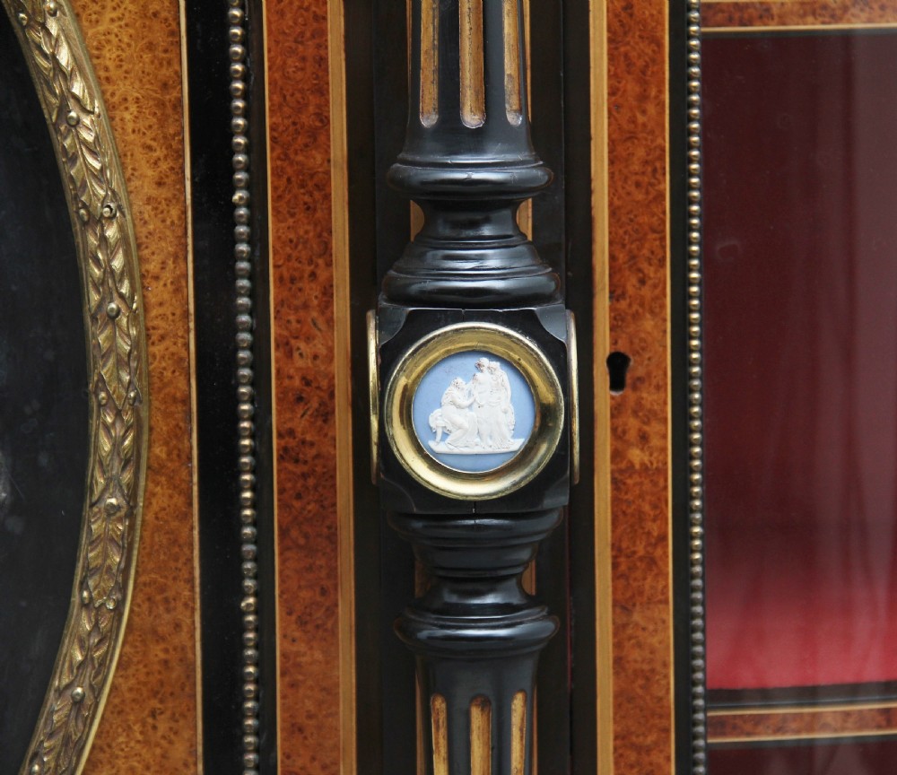A 19th-century ebonised and amboyna wood credenza featuring central doors with oval pietre dure panels, porcelain medallion inserts, gilt bronze mounts, and curved glass side compartments. View XXIV
