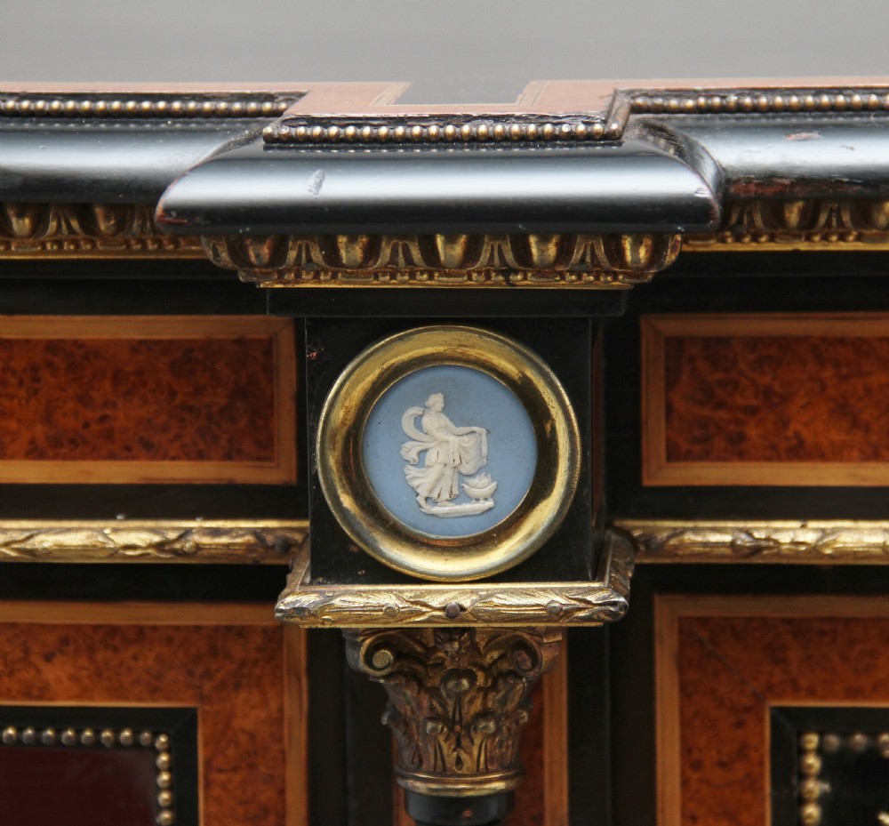 A 19th-century ebonised and amboyna wood credenza featuring central doors with oval pietre dure panels, porcelain medallion inserts, gilt bronze mounts, and curved glass side compartments. View XXV