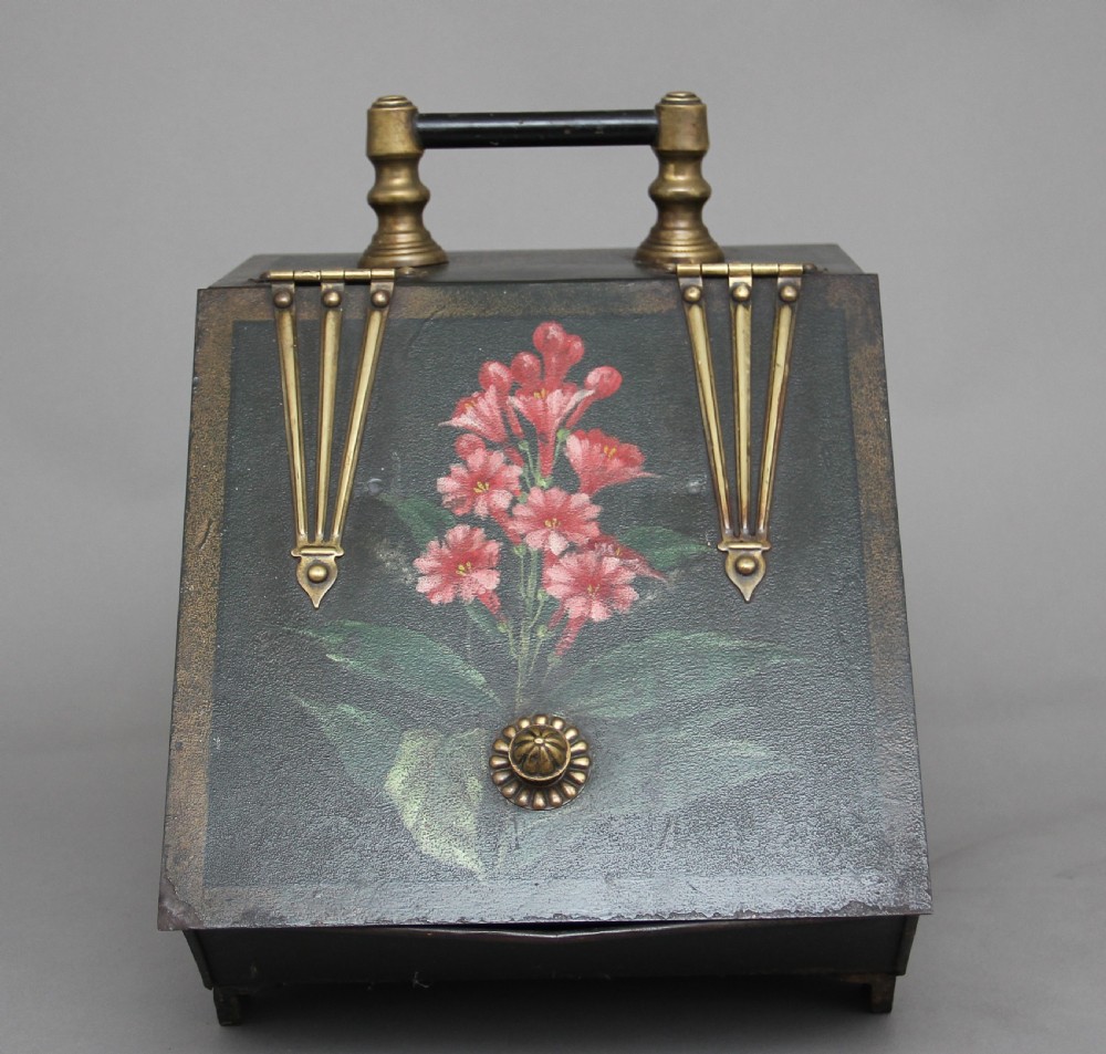 A nineteenth-century black metal coal box featuring a slanted drop front decorated with hand-painted pink flowers, brass strap hinges, a brass knob, and a top carrying handle. View V
