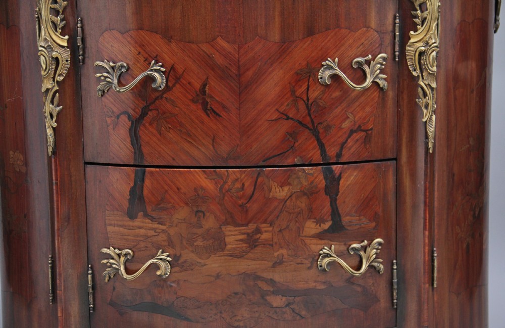 An early 19th-century French marquetry cabinet with a curved front, marble top, detailed wood inlay depicting a scenic landscape, and ornamental brass mounts. View III