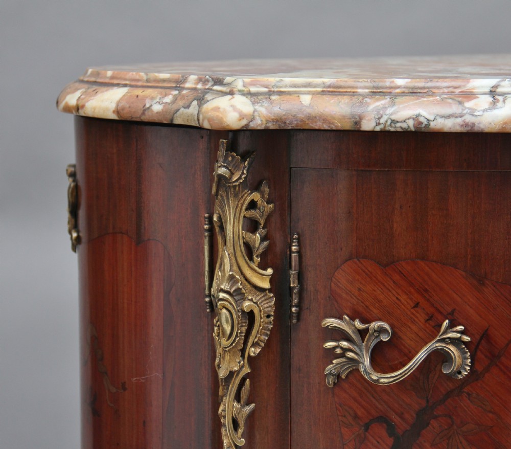 An early 19th-century French marquetry cabinet with a curved front, marble top, detailed wood inlay depicting a scenic landscape, and ornamental brass mounts. View IV