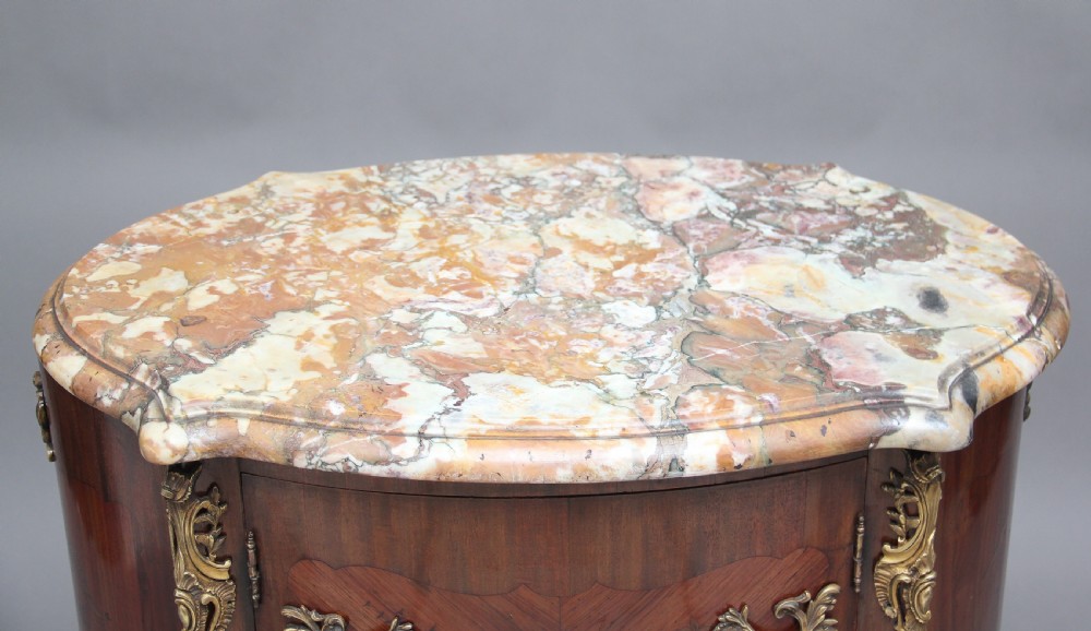 An early 19th-century French marquetry cabinet with a curved front, marble top, detailed wood inlay depicting a scenic landscape, and ornamental brass mounts. View V