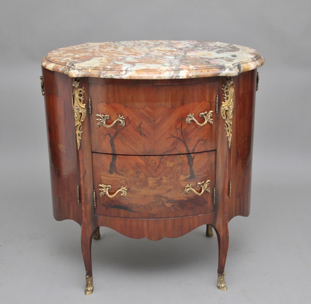 An early 19th-century French marquetry cabinet with a curved front, marble top, detailed wood inlay depicting a scenic landscape, and ornamental brass mounts. View VI