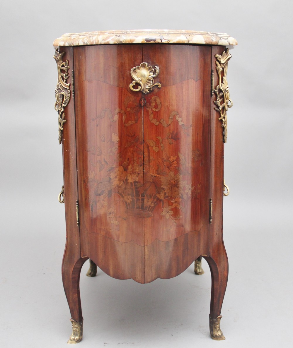 An early 19th-century French marquetry cabinet with a curved front, marble top, detailed wood inlay depicting a scenic landscape, and ornamental brass mounts. View VII