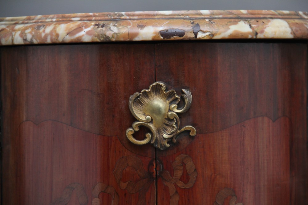 An early 19th-century French marquetry cabinet with a curved front, marble top, detailed wood inlay depicting a scenic landscape, and ornamental brass mounts. View IX