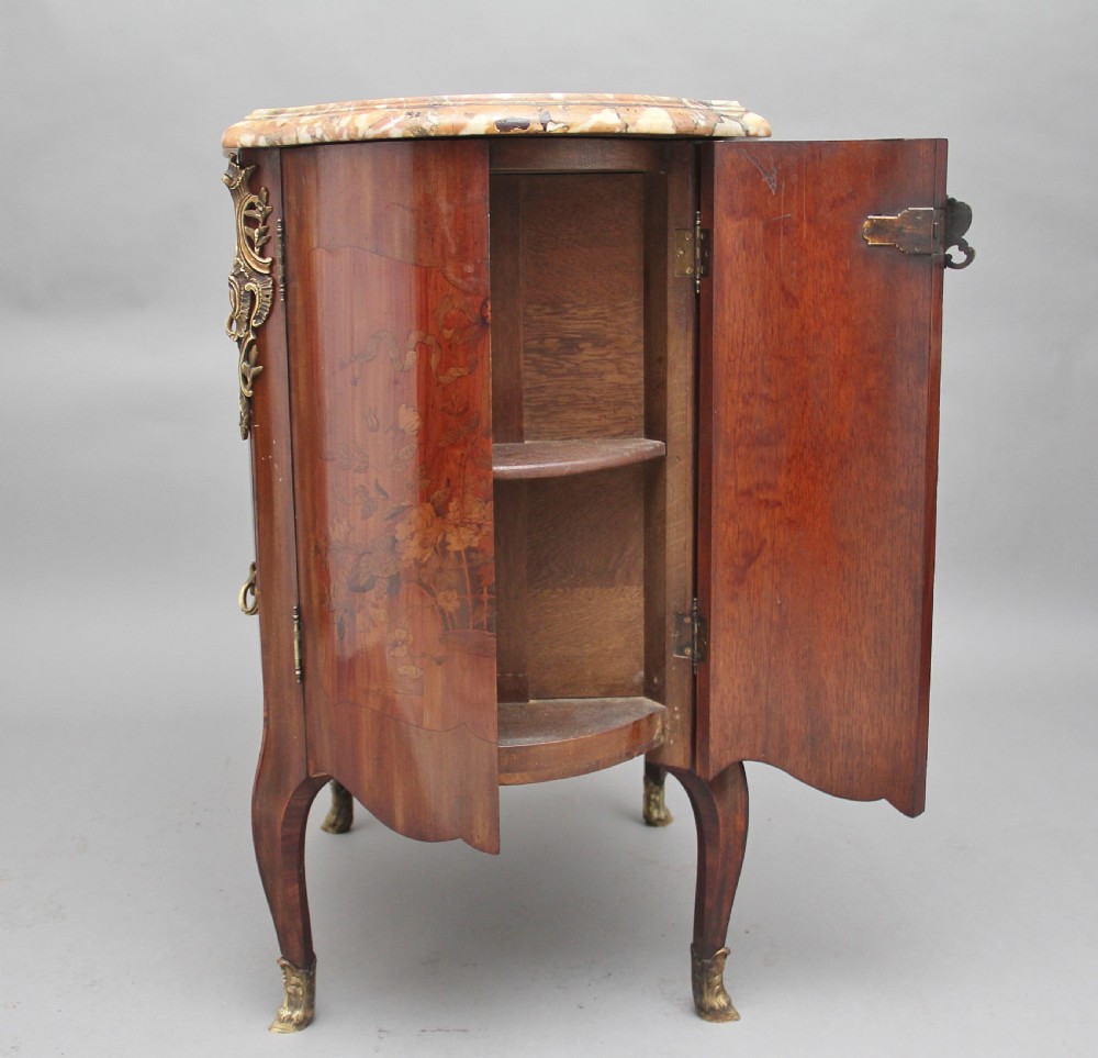 An early 19th-century French marquetry cabinet with a curved front, marble top, detailed wood inlay depicting a scenic landscape, and ornamental brass mounts. View X