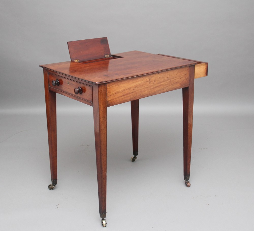 An early nineteenth-century mahogany writing table featuring square tapered legs on brass castors, a single drawer with turned wooden handles, and an adjustable reading slope set into the top. View III