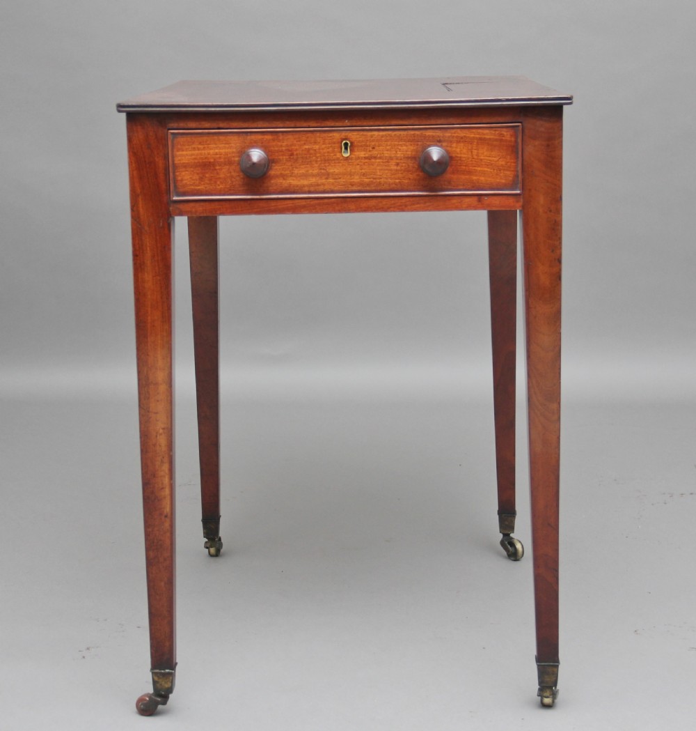 An early nineteenth-century mahogany writing table featuring square tapered legs on brass castors, a single drawer with turned wooden handles, and an adjustable reading slope set into the top. View VIII