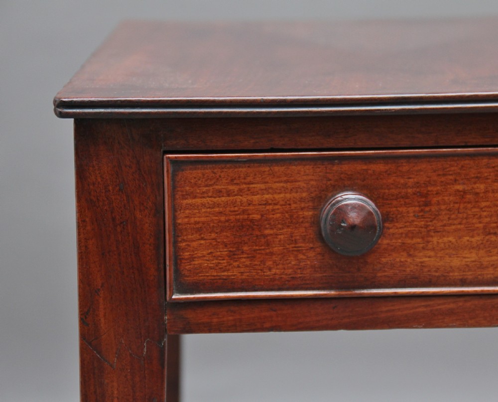 An early nineteenth-century mahogany writing table featuring square tapered legs on brass castors, a single drawer with turned wooden handles, and an adjustable reading slope set into the top. View X
