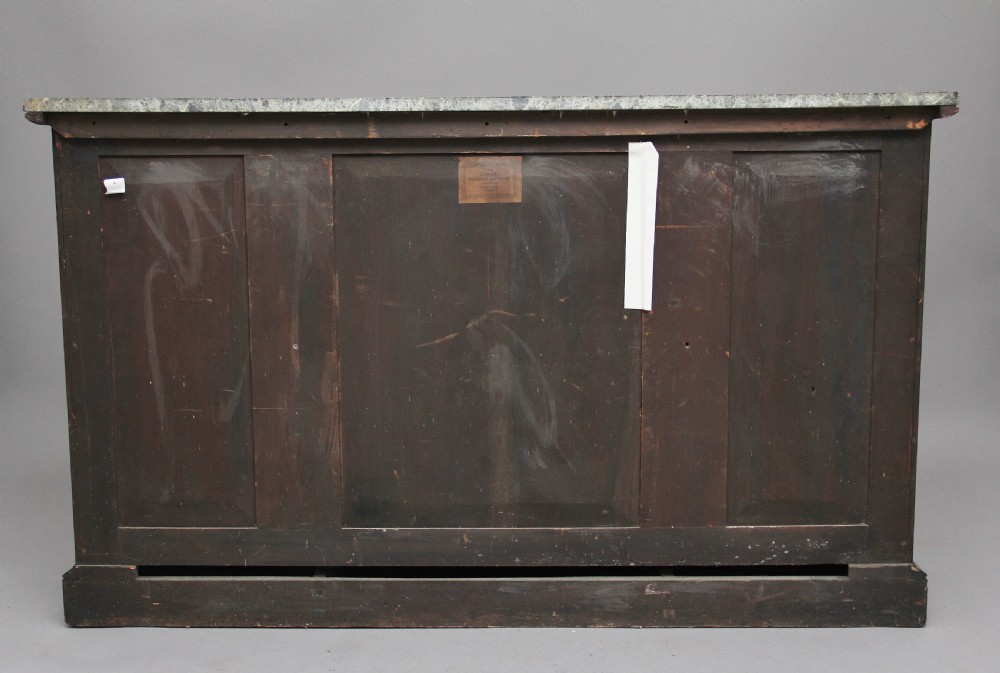 An early nineteenth-century rosewood breakfront cabinet featuring a green marble top, open central shelving section, and flanking doors with pleated fabric panels on a solid plinth base. View VII