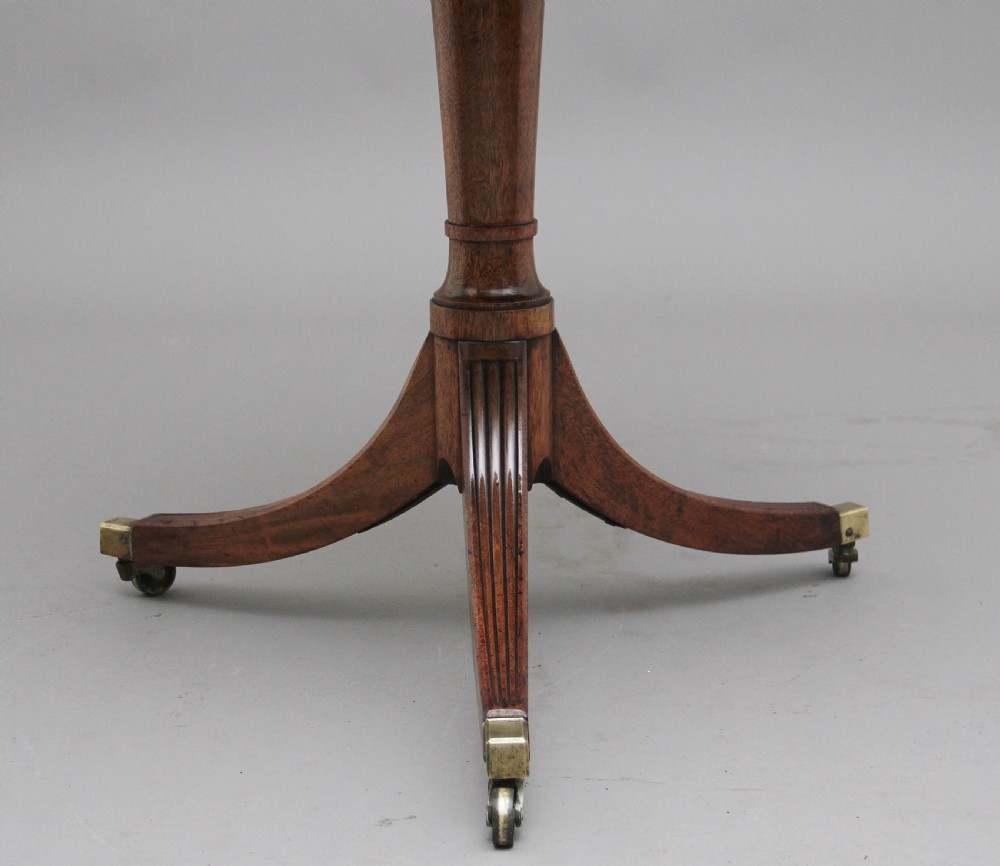 An early nineteenth-century mahogany two-tier dumbwaiter featuring circular drop-leaf surfaces, a turned central column support, and reeded tripod legs with brass castors. View XI
