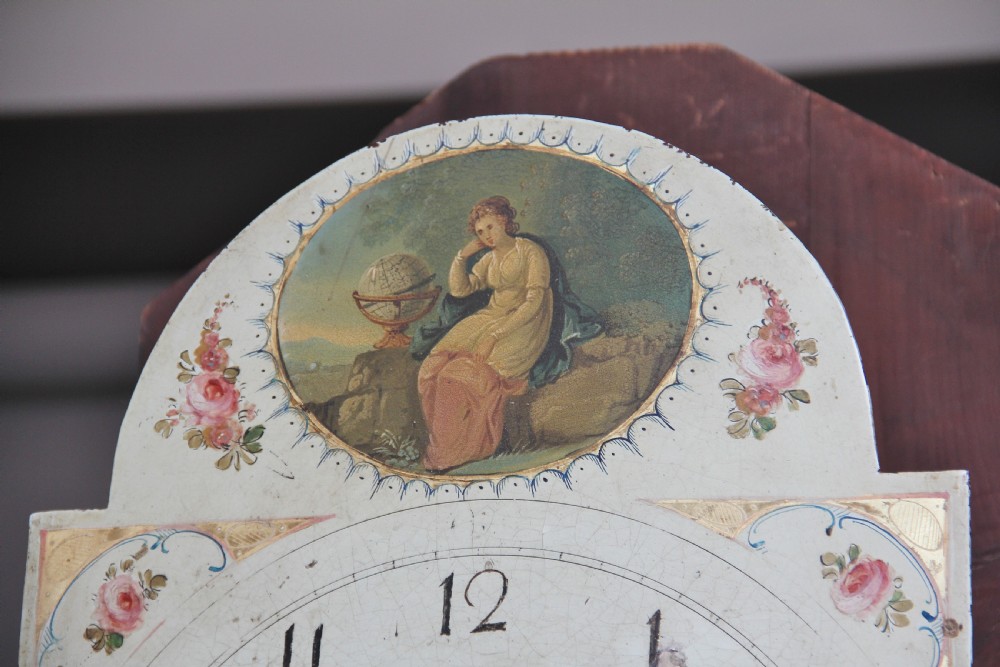 A 19th-century mahogany longcase clock featuring a swan-neck pediment hood, an arched painted clock dial, a flame mahogany trunk door with marquetry inlay, and a plinth base. View IV