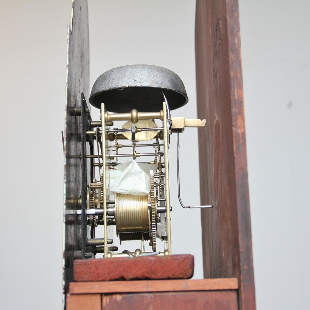 A 19th-century mahogany longcase clock featuring a swan-neck pediment hood, an arched painted clock dial, a flame mahogany trunk door with marquetry inlay, and a plinth base. View VI