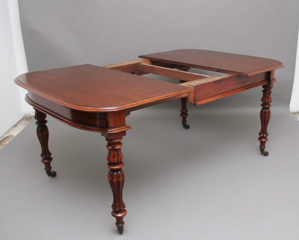 A 19th-century mahogany extending dining table with rounded corners, a polished rectangular top, turned legs, and brass castors. View III