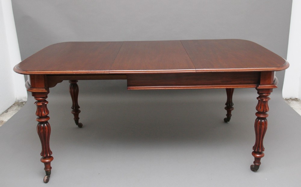 A 19th-century mahogany extending dining table with rounded corners, a polished rectangular top, turned legs, and brass castors. View VI
