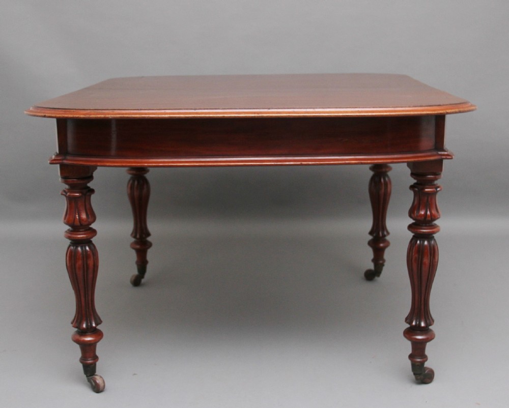 A 19th-century mahogany extending dining table with rounded corners, a polished rectangular top, turned legs, and brass castors. View VII