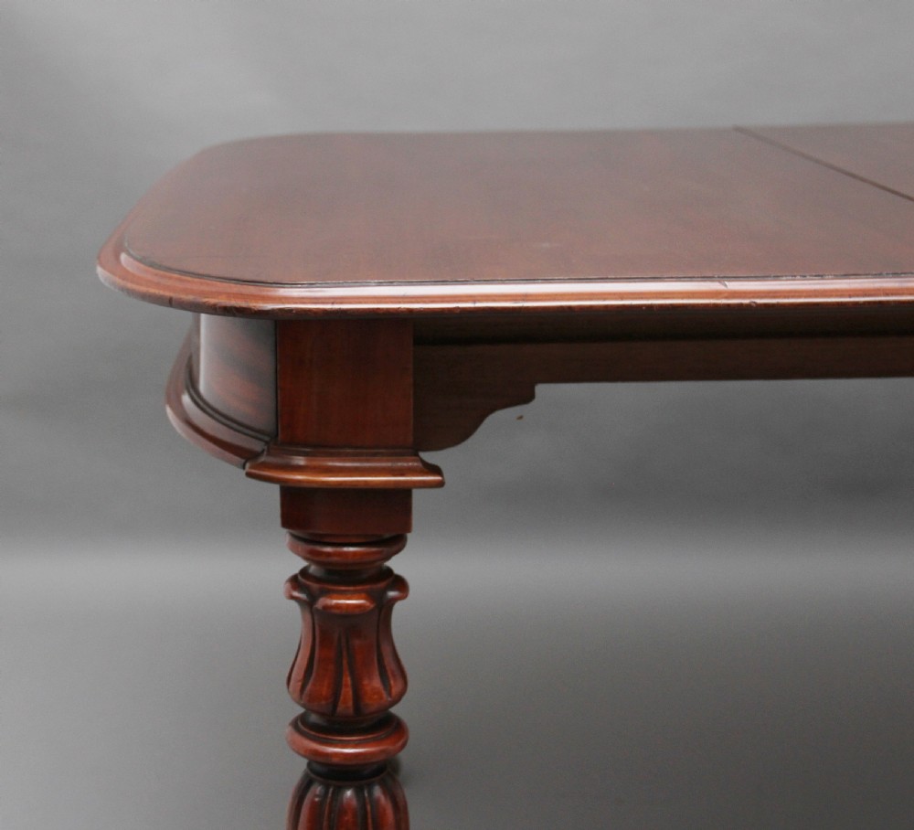 A 19th-century mahogany extending dining table with rounded corners, a polished rectangular top, turned legs, and brass castors. View IX