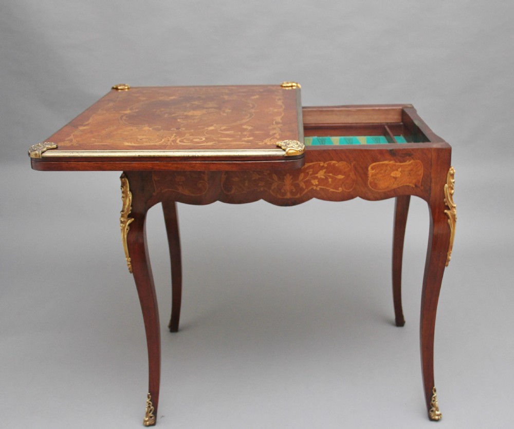 A 19th-century French Rococo revival kingwood fold-over card table with floral marquetry inlay, cabriole legs, and ornate gilt ormolu mounts. View V
